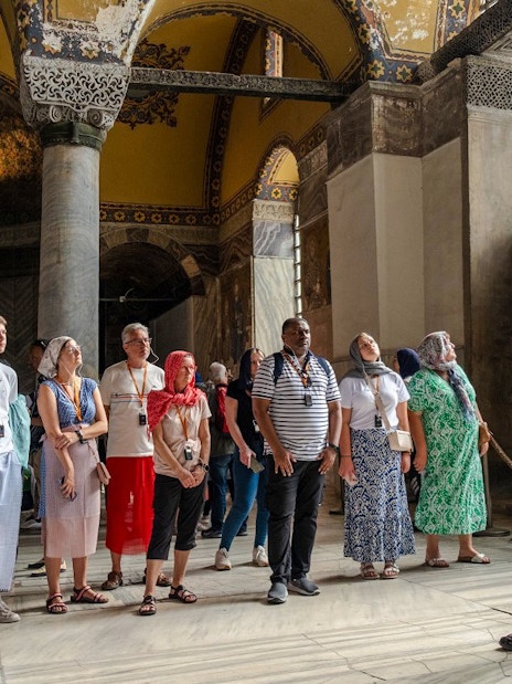 Guided tour group inside Hagia Sophia, Istanbul, observing architectural details.