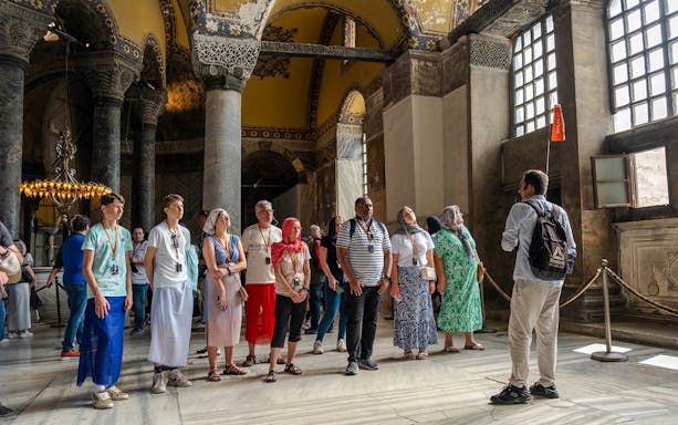 Guided tour group inside Hagia Sophia, Istanbul, observing architectural details.