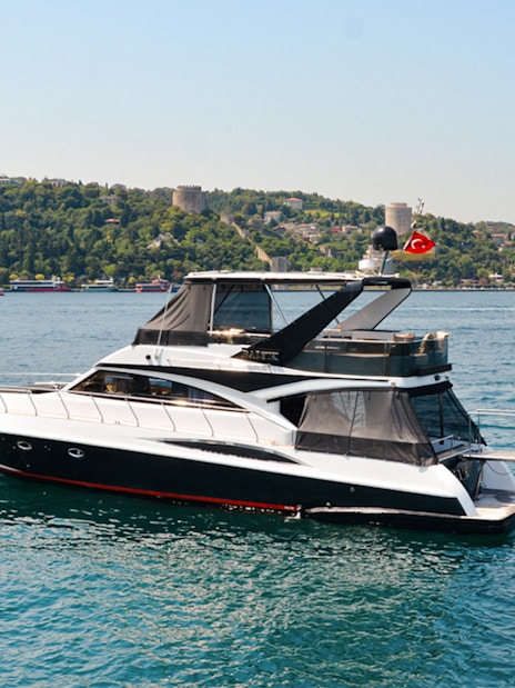 Luxury private yacht cruising on the Bosphorus with Istanbul skyline and bridge in the background.
