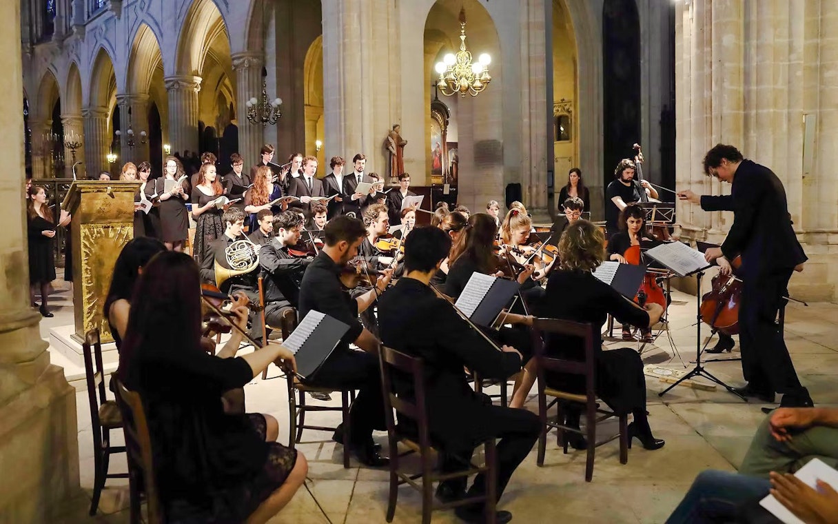 Orchestra performing in St Sulpice Church, Paris, with conductor and choir.