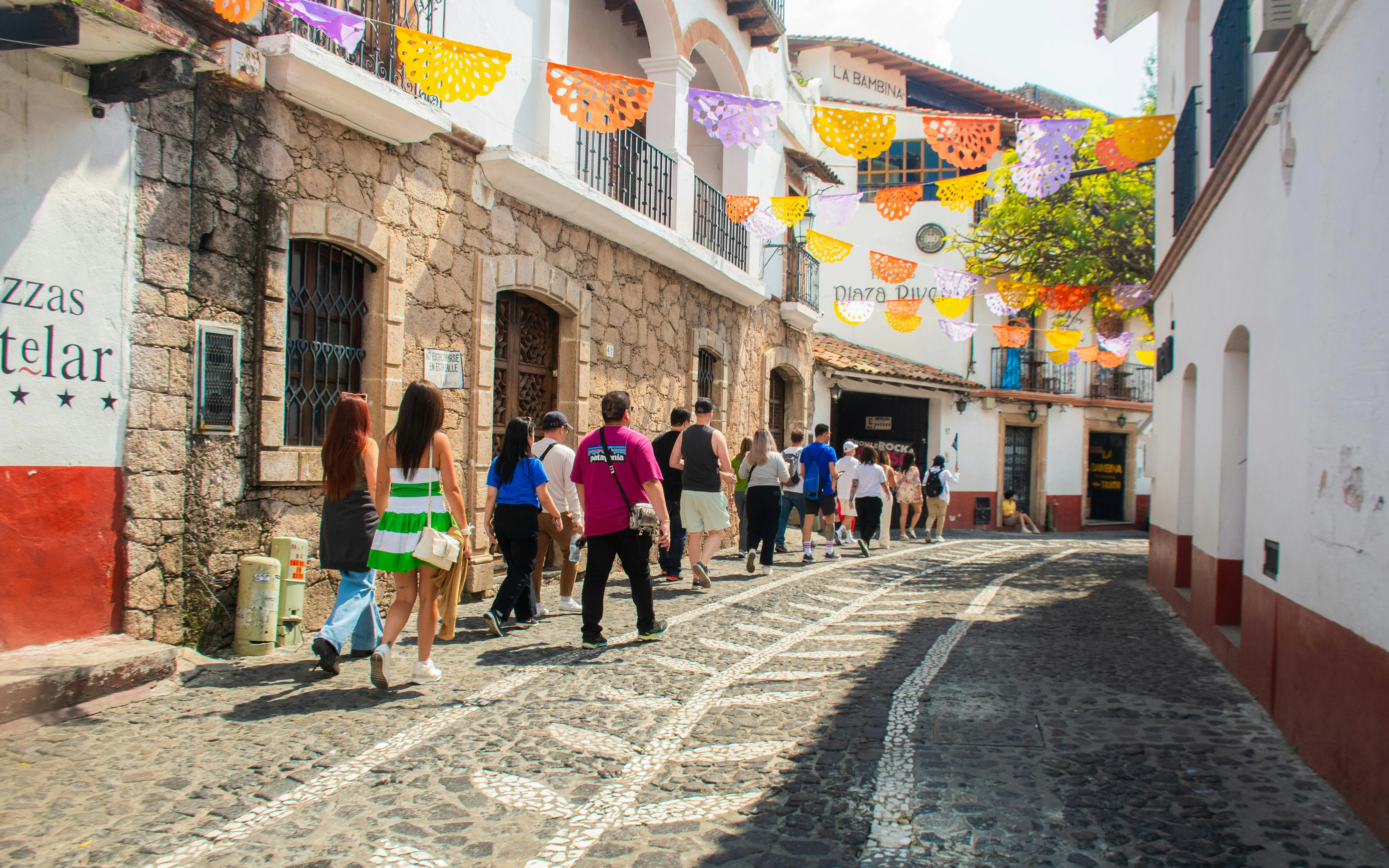 Tourists walking through a colorful street in Taxco, Mexico City day tour.