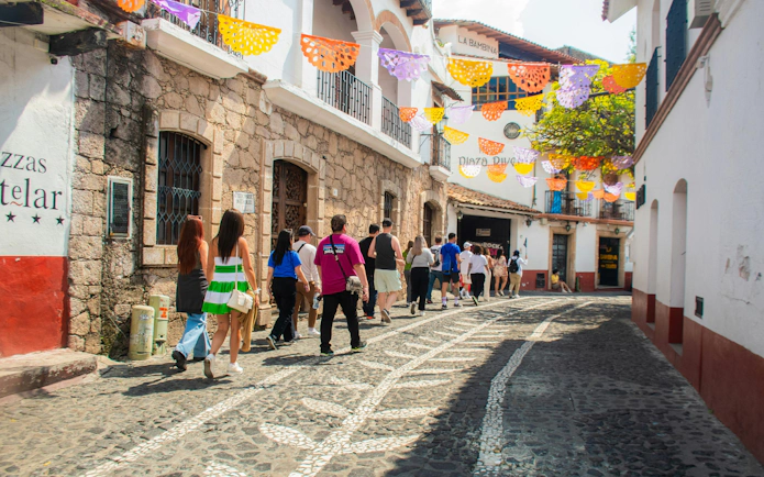 Tourists walking through a colorful street in Taxco, Mexico City day tour.