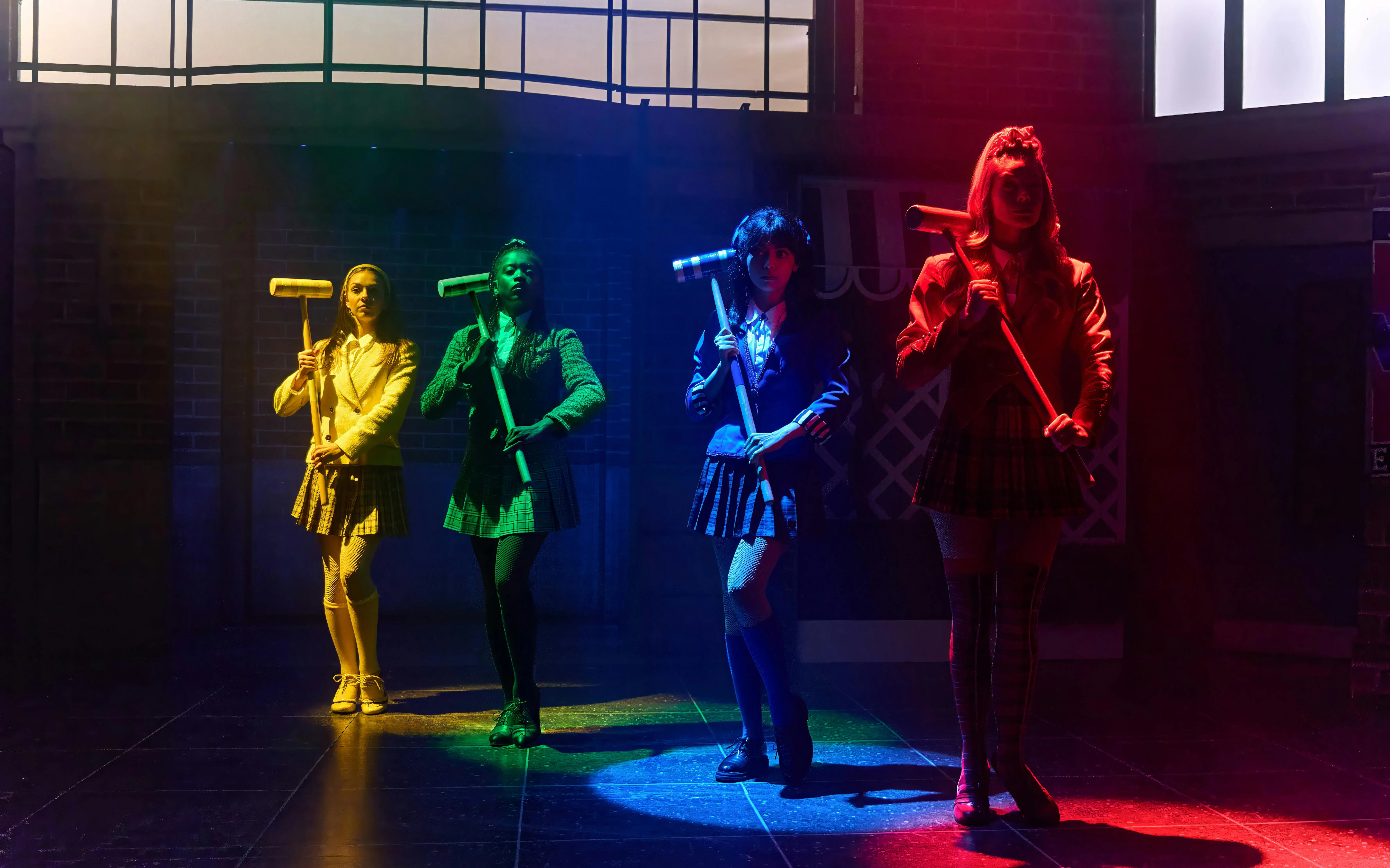 Performers on stage in Heathers The Musical holding croquet mallets.