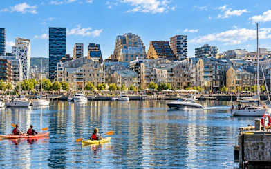 Kayakers on Oslo waterfront with modern buildings in the background.