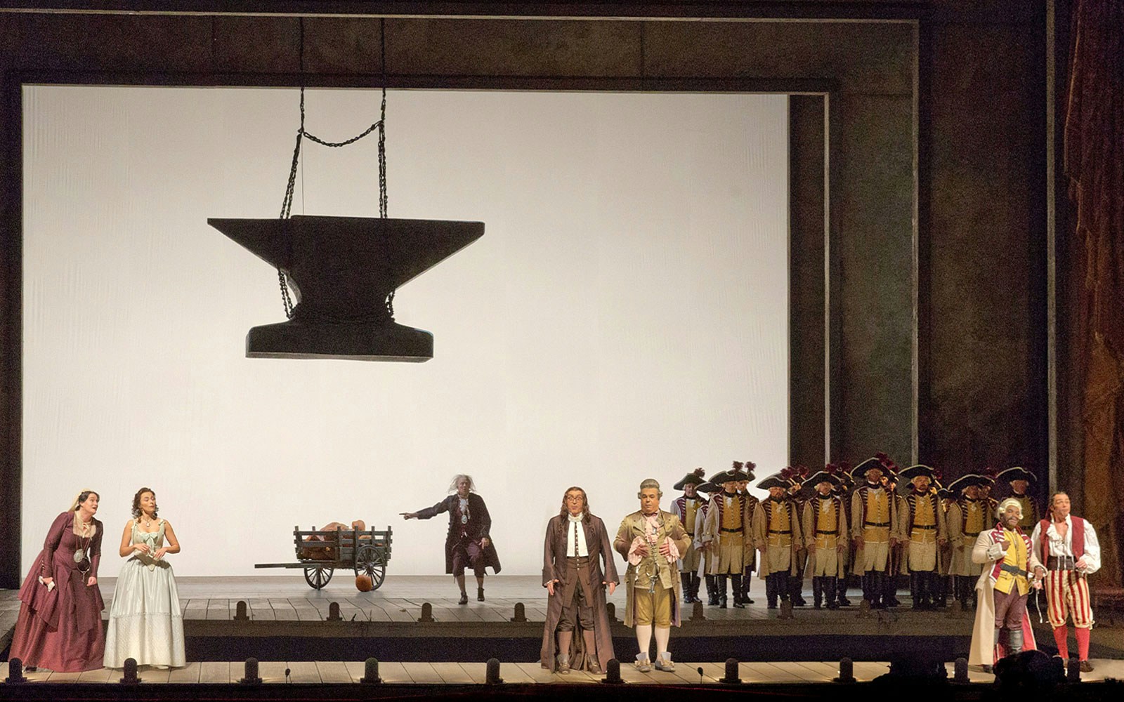 Il Barbiere Di Siviglia opera scene with performers on stage and large anvil backdrop.