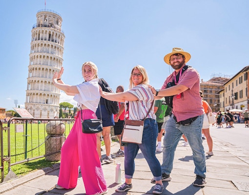 Visitors posing creatively with the Leaning Tower of Pisa in Italy.