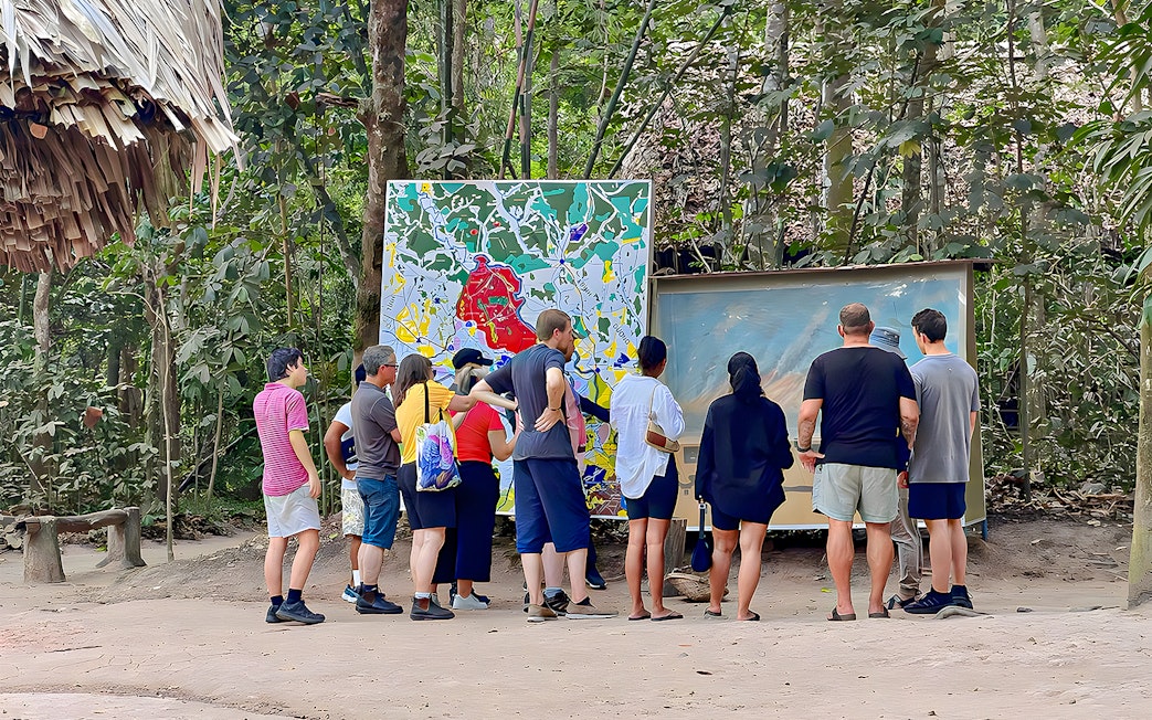 Tour group examining maps at Cu Chi Tunnels, Vietnam.