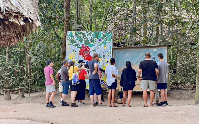Tour group examining maps at Cu Chi Tunnels, Vietnam.