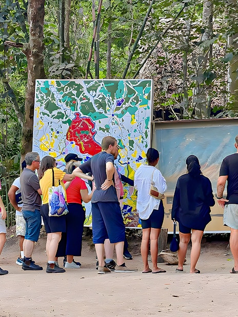 Tour group examining maps at Cu Chi Tunnels, Vietnam.
