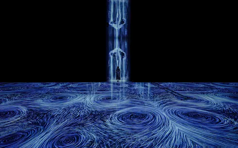 Interactive digital art installation with swirling blue vortices and a person standing in the flow.