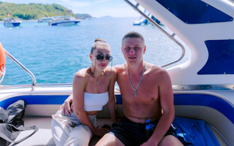 Couple enjoying a speed boat ride on a sunny day with scenic ocean views.