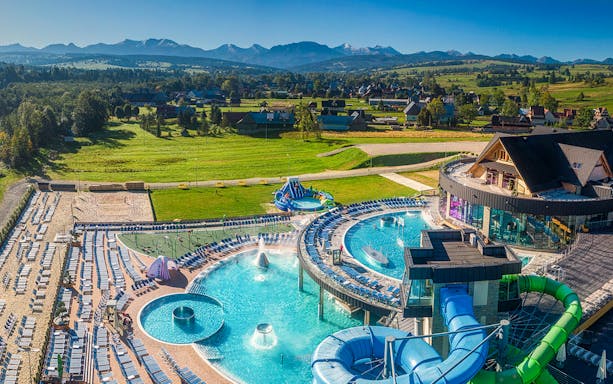 Chocholow Thermal Baths with pools and slides, surrounded by scenic mountain landscape.