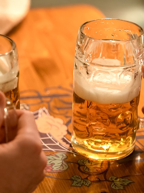 Hands holding beer mugs on a wooden table.