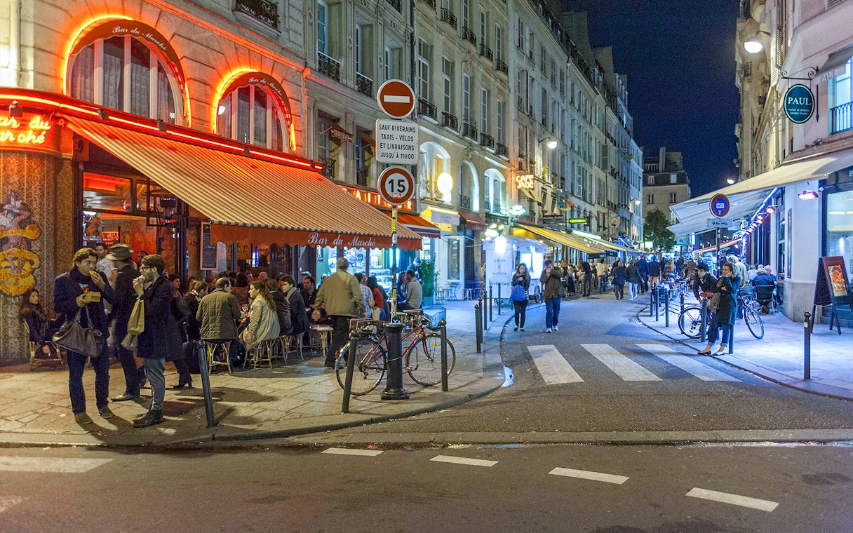 Paris street scene with cafes and pedestrians at night.