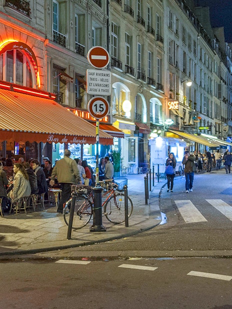 Paris street scene with cafes and pedestrians at night.