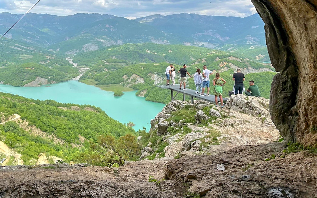 Guests on a platform overlooking Bovilla Lake surrounded by lush mountains.