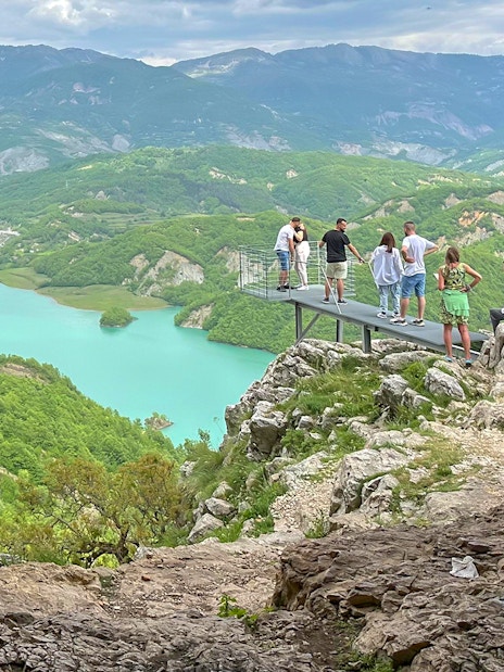 Guests on a platform overlooking Bovilla Lake surrounded by lush mountains.