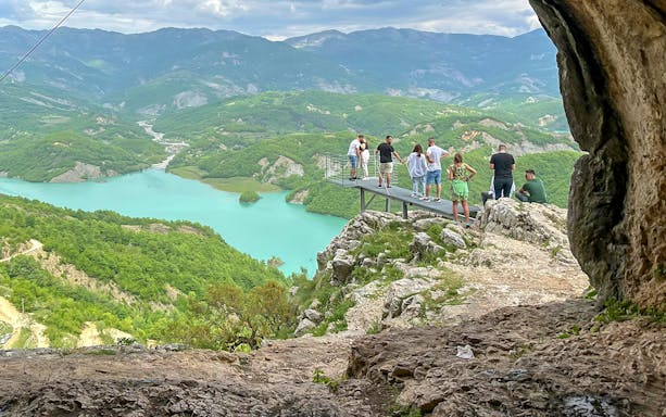 Guests on a platform overlooking Bovilla Lake surrounded by lush mountains.