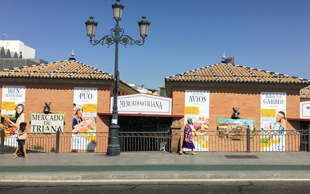 Mercado de Triana entrance in Seville, Spain, with people walking by.