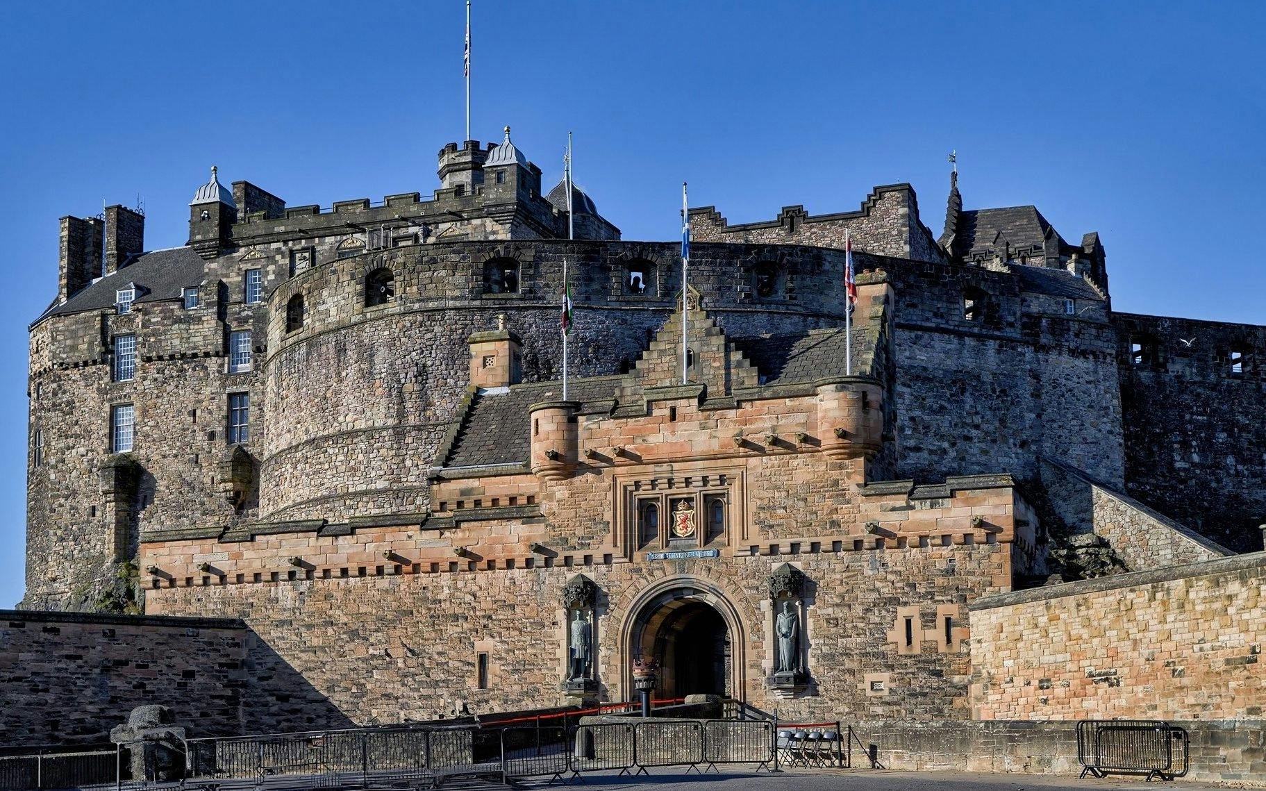Edinburgh Castle entrance with stone walls and flags.