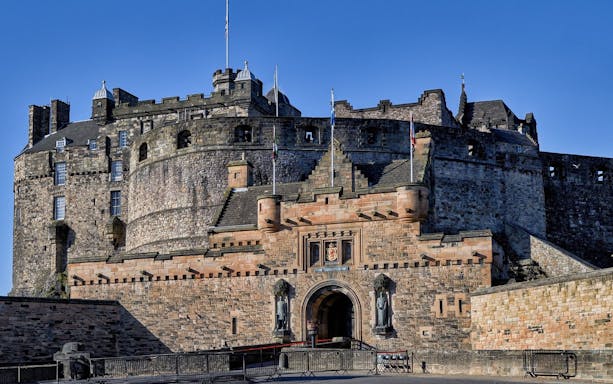Edinburgh Castle entrance with stone walls and flags.
