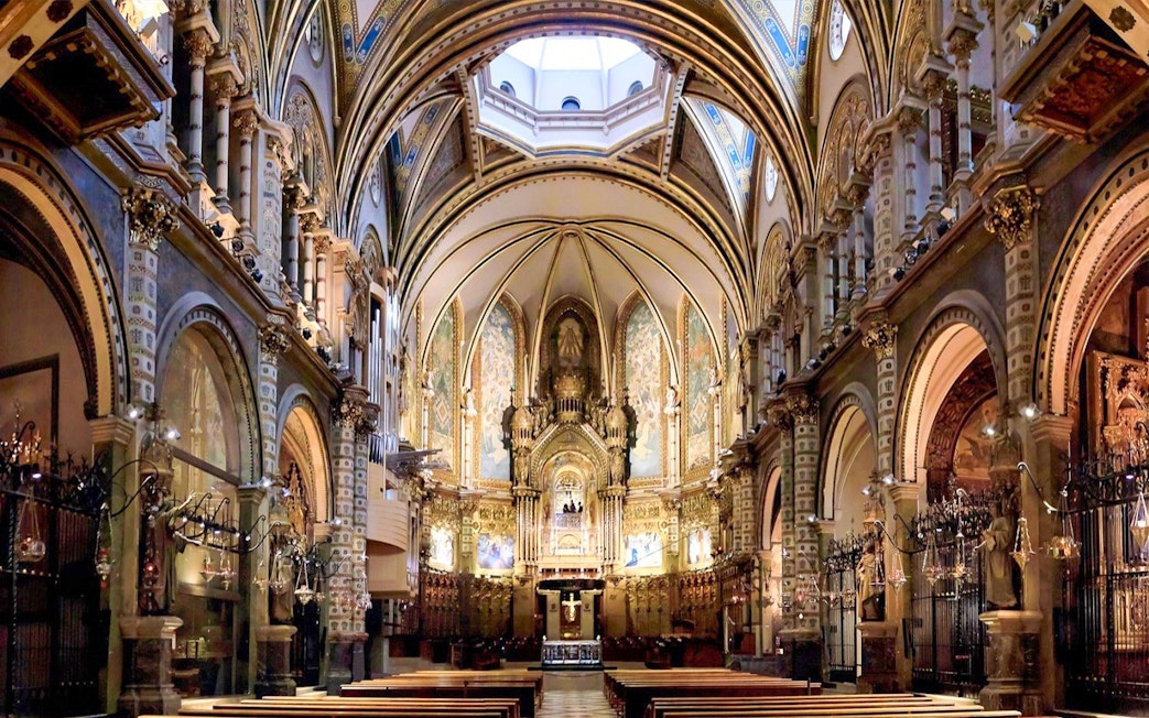 Interior of Montserrat Monastery's basilica with ornate arches and altar, part of Barcelona day trip.