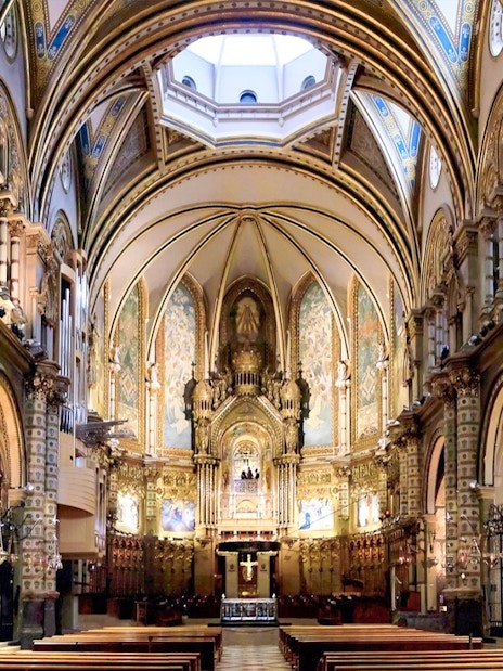 Interior of Montserrat Monastery's basilica with ornate arches and altar, part of Barcelona day trip.