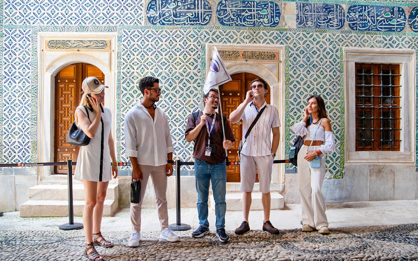 Tour group with guide at Topkapi Palace Museum, Istanbul, near ornate tiled wall.
