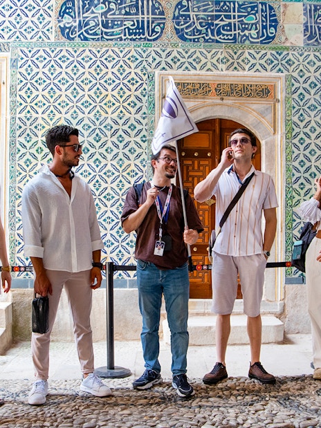 Tour group with guide at Topkapi Palace Museum, Istanbul, near ornate tiled wall.