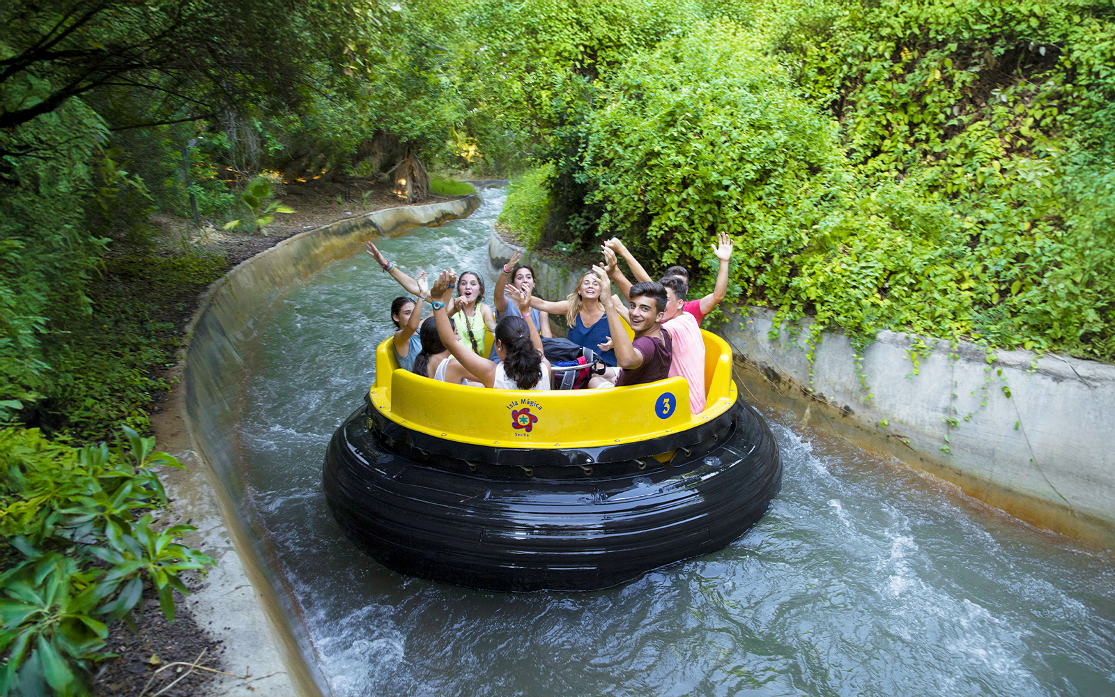 Visitors enjoying a lazy river ride at Isla Mágica, surrounded by lush greenery.