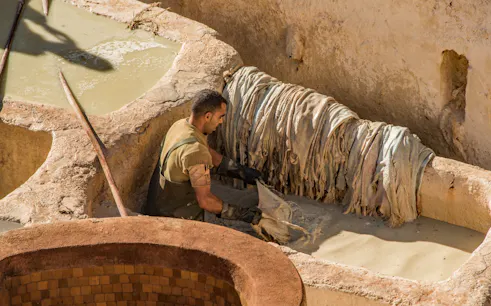 Worker processing leather in a tannery vat in Fes Medina.