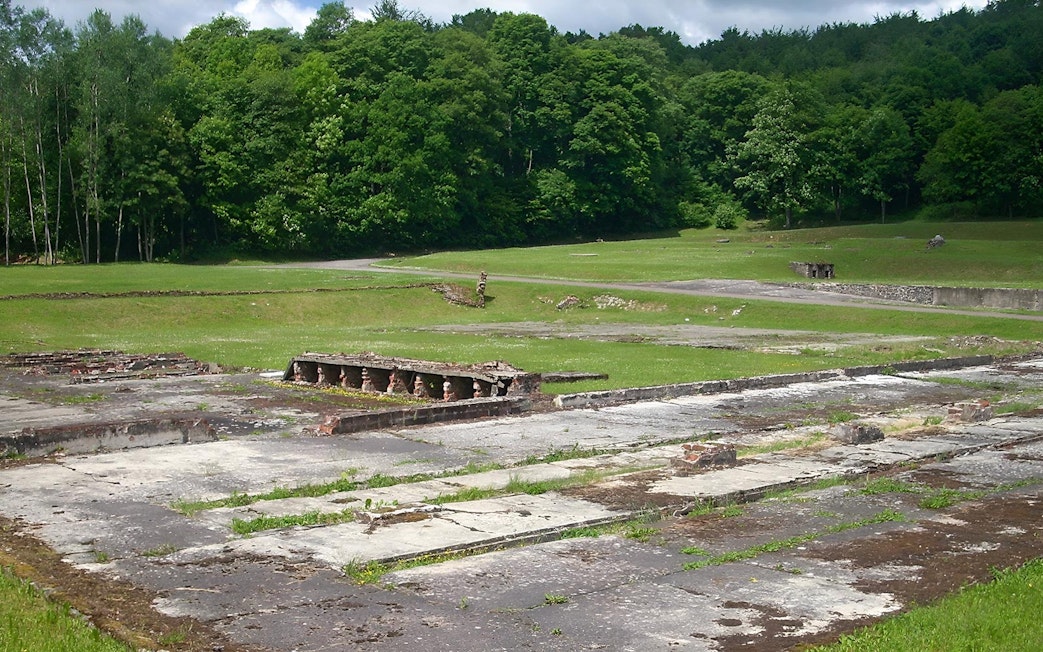 Ruins of Stutthof Concentration Camp surrounded by green forest.