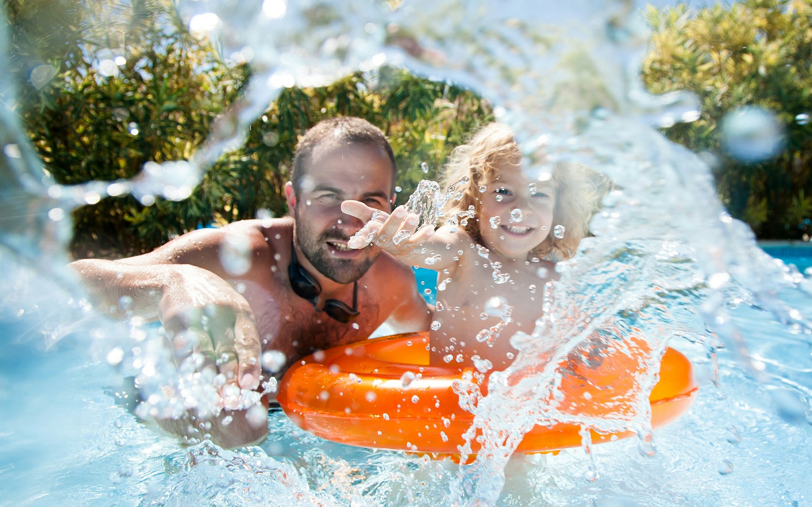 Father and child enjoying wave pool with orange float.