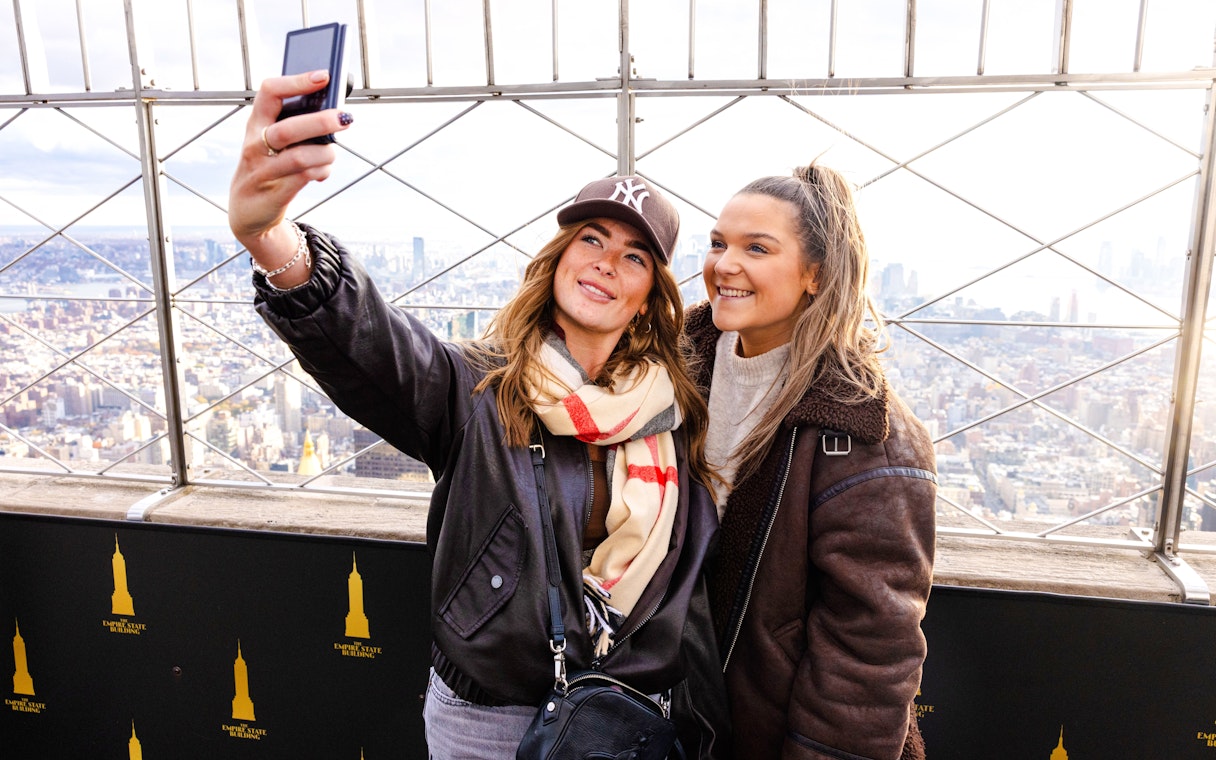 Guests taking a selfie at the Empire State Building observation deck, New York City.