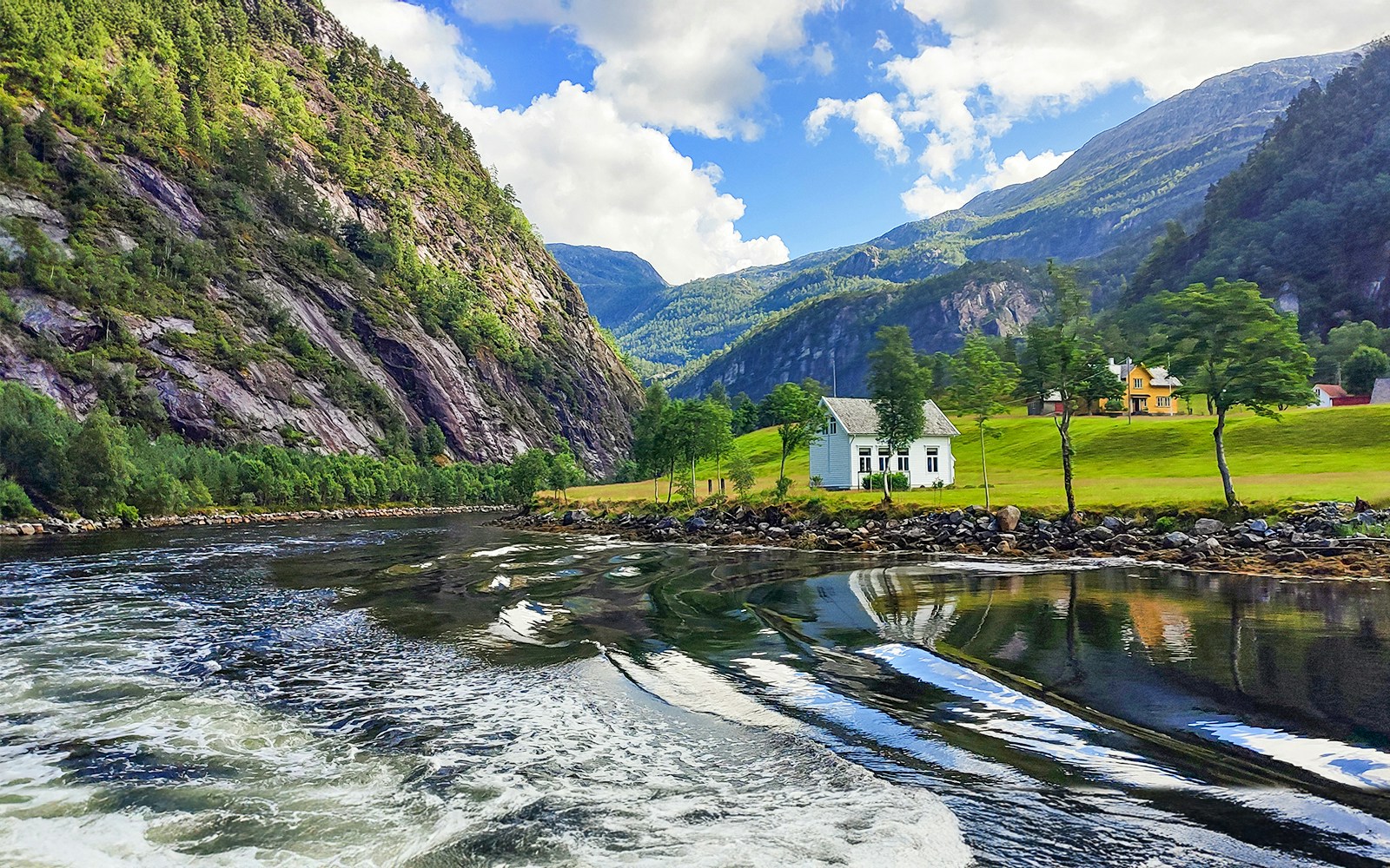 Cruise through Mostraumen Fjord near Bergen, Norway, with scenic mountains and houses.