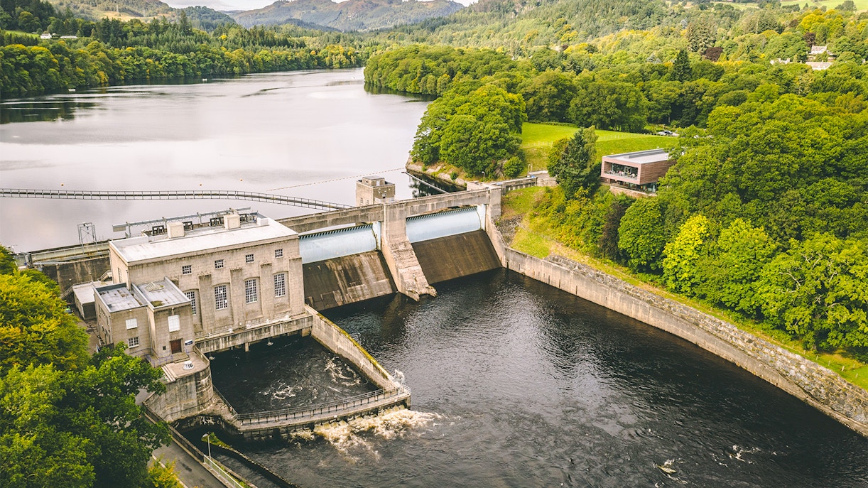 Pitlochry dam and hydroelectric power station surrounded by lush greenery, Scotland.