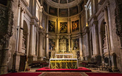 Altar inside Jeronimos Monastery, Lisbon, with ornate columns and religious artwork.