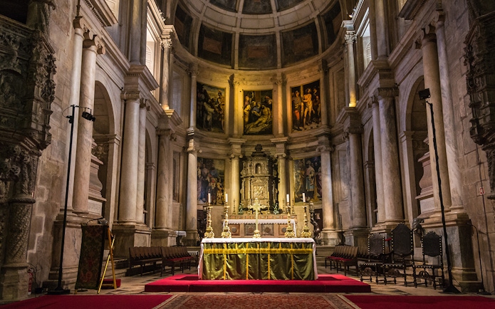 Altar inside Jeronimos Monastery, Lisbon, with ornate columns and religious artwork.