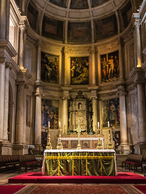 Altar inside Jeronimos Monastery, Lisbon, with ornate columns and religious artwork.