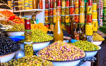 Bowls of olives and preserved goods at a vibrant souk in Marrakech.