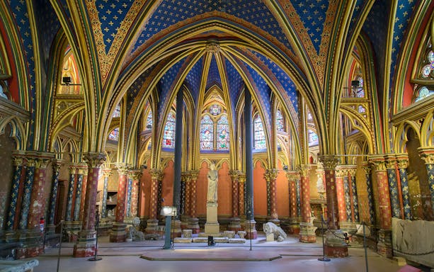 Lower chapel of Sainte Chapelle in Paris with colorful vaulted ceilings and stained glass windows.