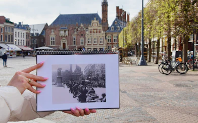 Haarlem WWII tour guide holding historic photo in city square.