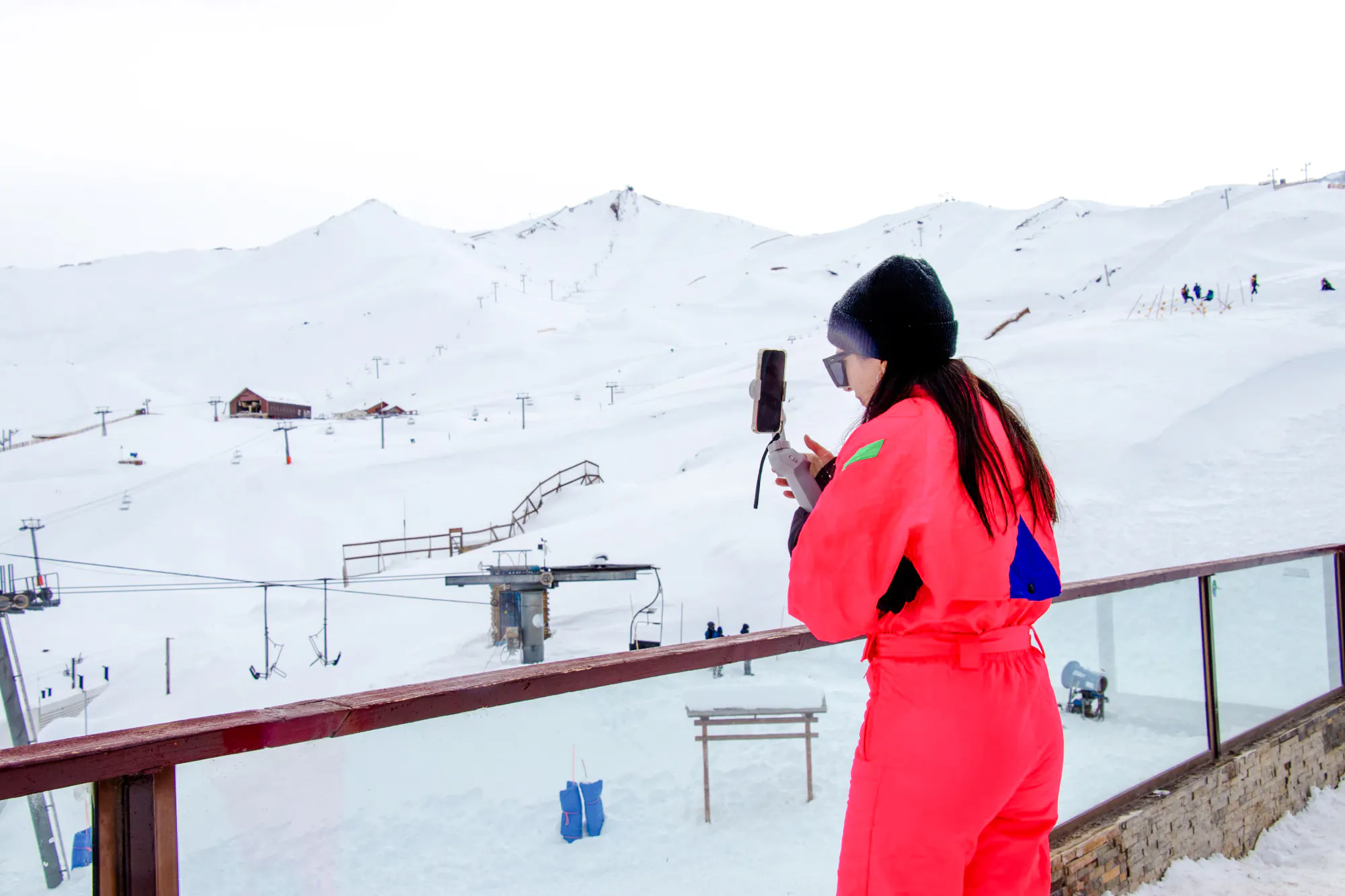 Person in bright outfit photographing snowy Valle Nevado ski slopes, Santiago.