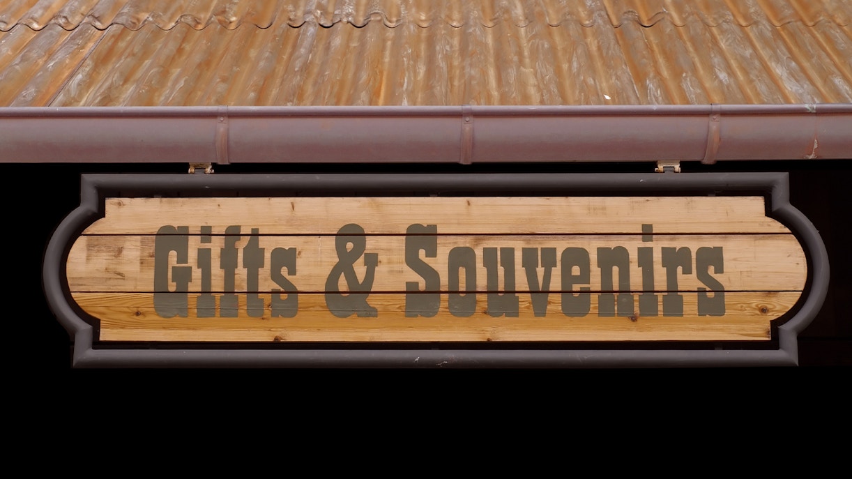 Gifts and souvenirs wooden sign under a metal roof.