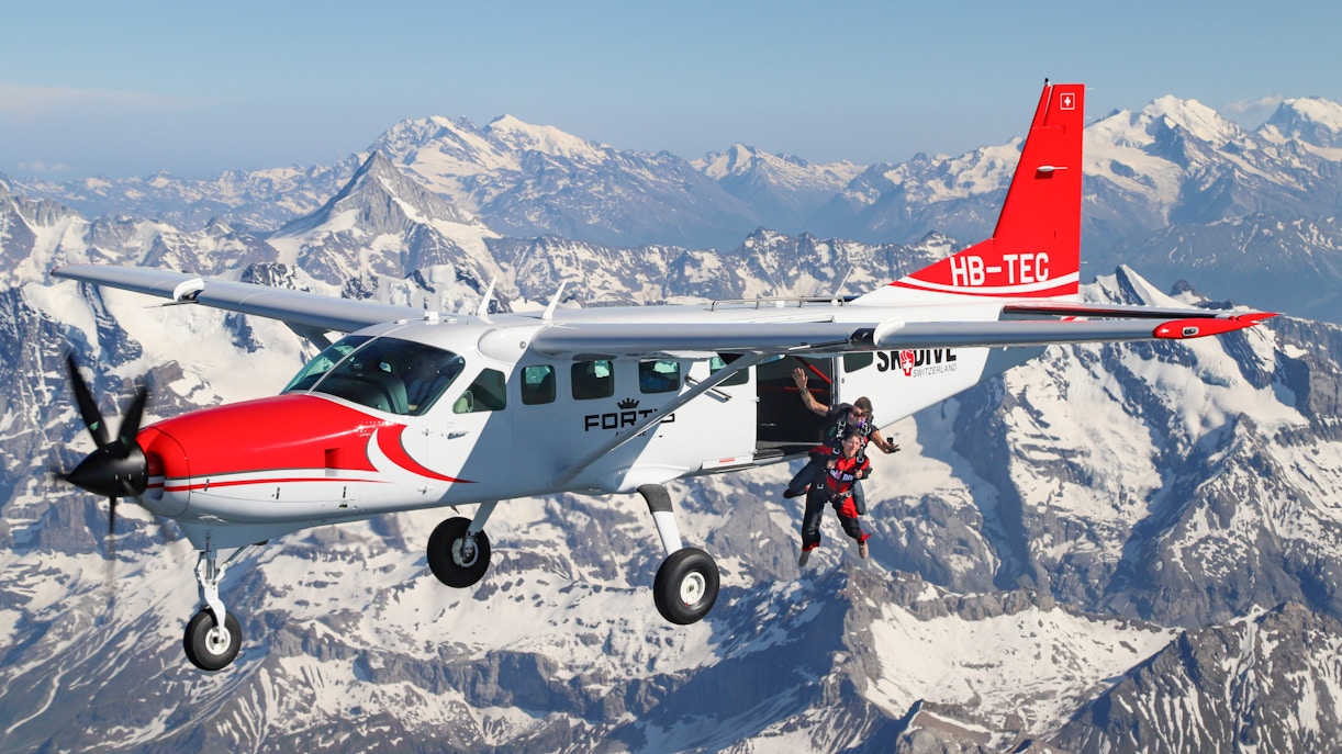 Skydivers jumping from a plane over the Swiss Alps.