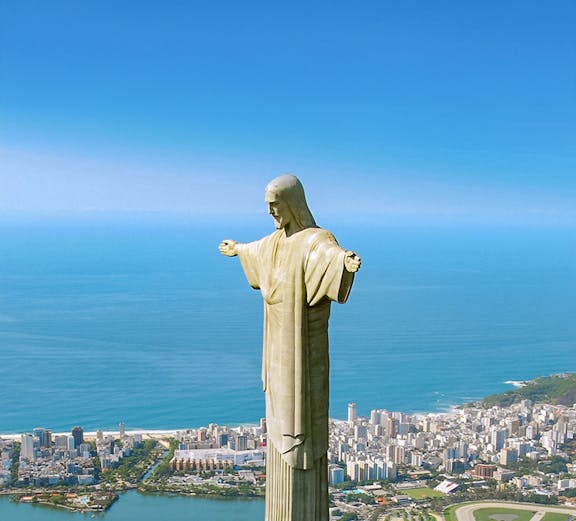 Christ the Redeemer statue overlooking Rio de Janeiro with cityscape and ocean in the background.