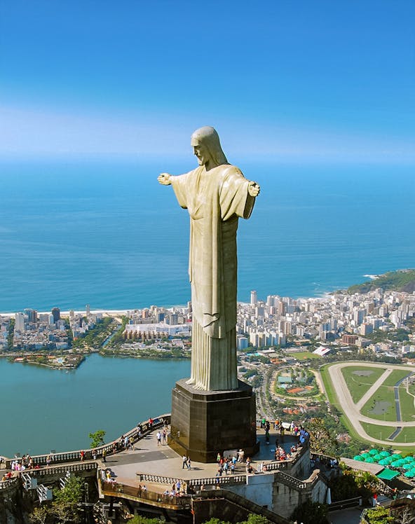 Christ the Redeemer statue overlooking Rio de Janeiro with cityscape and ocean in the background.