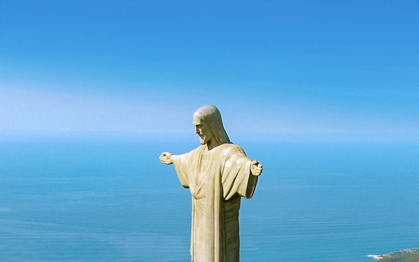 Christ the Redeemer statue overlooking Rio de Janeiro with cityscape and ocean in the background.