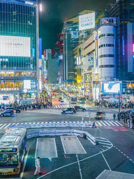 Shibuya Crossing view from Shibuya Sky Deck, Tokyo, with bustling crowds and illuminated buildings.