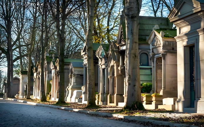 Tombs and trees lining a path inside Père Lachaise Cemetery, Paris.